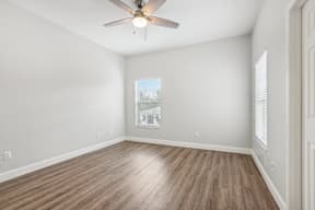 A room with a ceiling fan and wooden flooring.